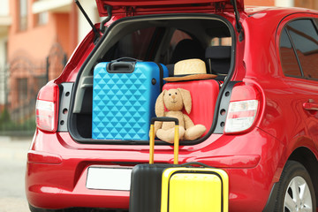 Suitcases, toy and hat in car trunk, closeup