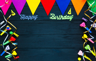 Happy birthday colorful  decoration: flags,candles, ribbons on the black wooden background