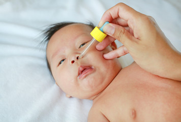 Obraz na płótnie Canvas Newborn baby gets nose drops. Baby care concept. 