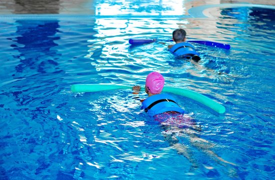 Two Child Siwmming in the Pool with Pool Noodle