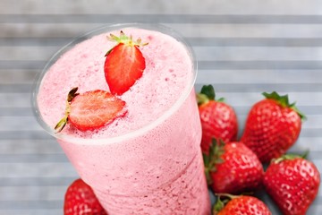 Glass of strawberry smoothie on wooden table