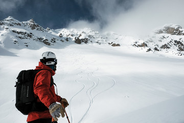 Fototapeta na wymiar Skier watches ski tracks in British Columbia backcountry