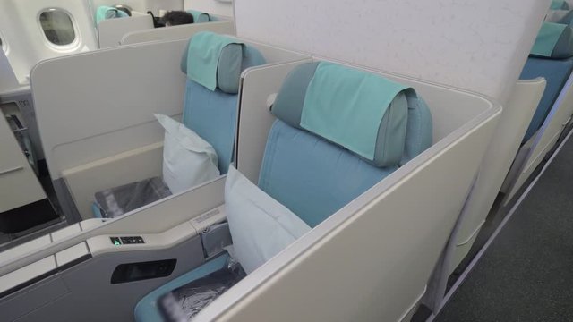 Comfortable empty seats in business class. Cabin interior in white and blue colors
