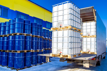 Discharge of plastic barrels. Barrels for the chemical industry. Blue metal barrels. White plastic containers. Chemical industry. The machine brought chemical substances. - obrazy, fototapety, plakaty