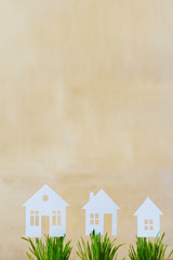 Paper models of houses in pots with a green grass on a wooden background