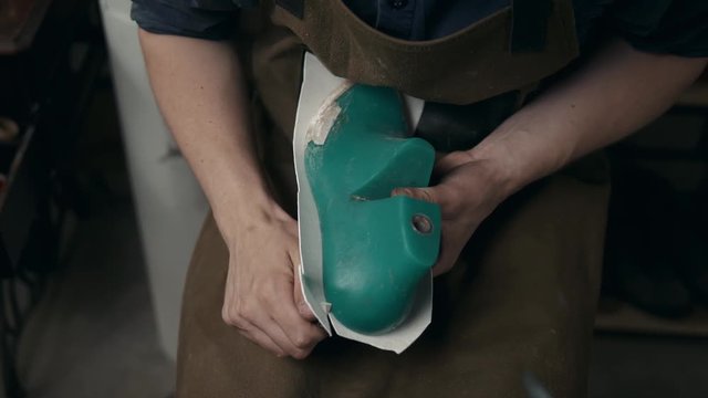 workers using a handtool to working on shoe component in footwear factory leather shoemaker