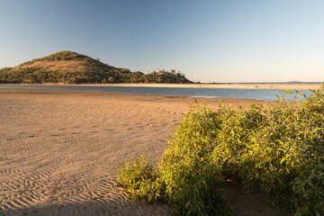 The beach at the outlet of Mulambin Creek in golden, evening light.