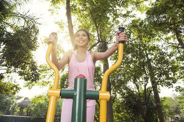 Smiling asian woman doing workout on elliptical machine