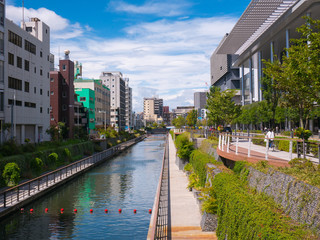Obraz na płótnie Canvas Canal with pedestrian and bicycle path, in a hot sunny day with few clouds. Tokyo, Japan.