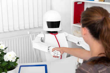 Autonomer Roboter als Arzt in einer Praxis, Frau schüttelt ihm die Hand