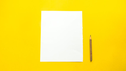 Paper and pencil on yellow background