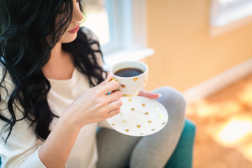Young woman drinking coffee in a chair in her home
