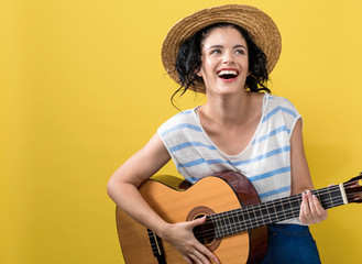 Young woman with a guitar on a yellow background