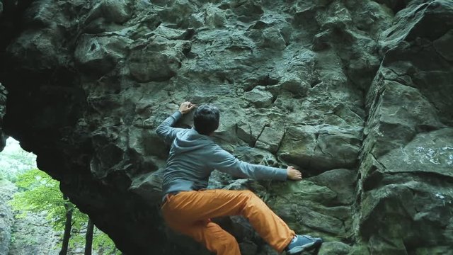 man climbing bouldering route on the cliff in the wood