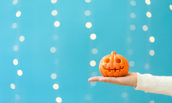 Woman holding a halloween pumpkin on a shiny light blue background