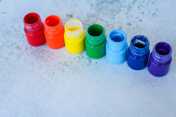 rainbow Gouache or acrylic paints in jars on white grunge background, selective focus