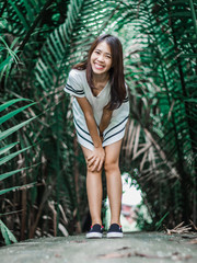 Obraz na płótnie Canvas A woman wearing dress white and having beautiful smile on the tree background , style dark green tone,bang krachao island in samut prakan at Thailand.