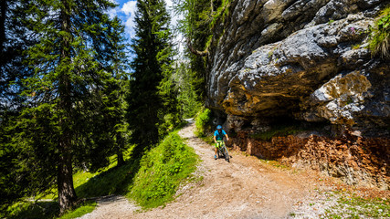 Tourist cycling in Cortina d'Ampezzo, stunning rocky mountains on the background. Man riding MTB enduro flow trail. South Tyrol province of Italy, Dolomites.