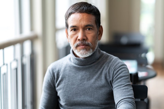 Portrait of unhappy angry mature asian man with stylish short beard looking at cemera with negative suspicious. Casual retired hispanic people feeling worry or unpleasant at outside cafe concept.