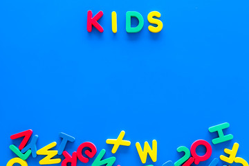 Early childhood development concept. Word kids written by plastic letters of toy alphabet on blue background top view copy space