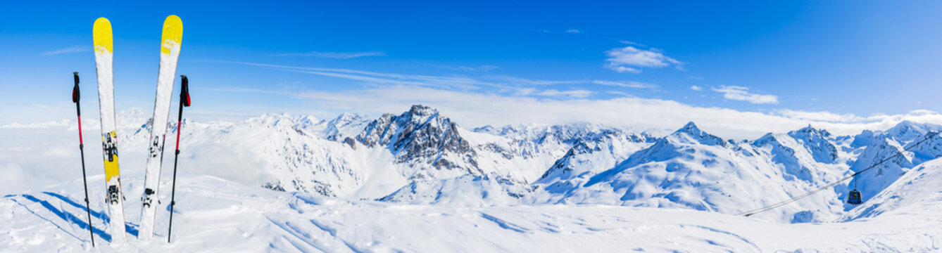 Ski in winter season, mountains and ski touring equipments on the top in sunny day in France, Alps above the clouds.