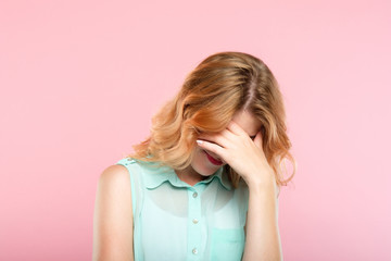 facepalm embarrassment and shame emotion. ashamed smiling girl covering her face with a hand. young beautiful woman portrait on pink background. - obrazy, fototapety, plakaty