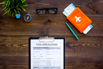 Planning a vacation, planning a trip. Visa application form near passport and airplane ticket on dark wooden background top view