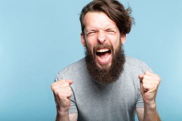anger and fury. emotional or mental breakdown. enraged man screaming. portrait of a young bearded...