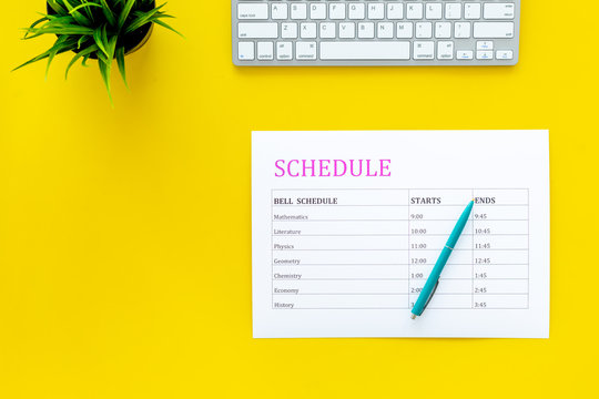 School student's schedule with time of lessons on yellow office desk with computer keyboard top view copy space