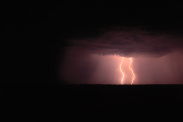 Two lightning strikes from the sky into the earth at night