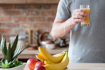 healthy morning tradition of freshly squeezed fruit juice. unrecognizable man holding a glass of natural organic banana and nectarine beverage. balanced diet and nutrition.