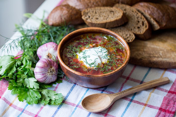 Fototapeta na wymiar Homemade Russian, Ukrainian and Polish national soup. Red borscht made of beetroot, vegetables, meat with sour cream with rye bread and garlic.