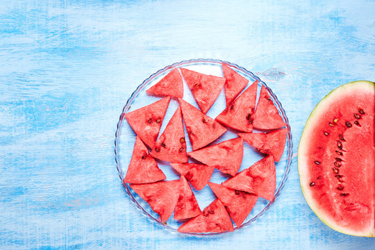Watermelon slices on the glass plate on blue background. Top view, flat lay.