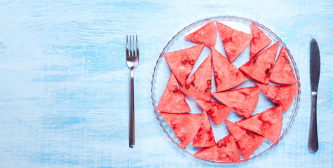 Watermelon slices on the glass plate on blue background. Top view, flat lay.