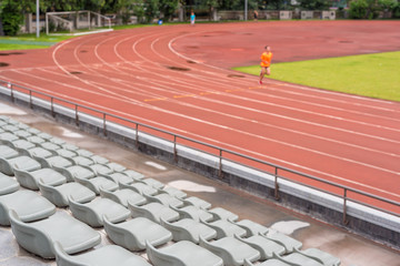 Selective focus on seats in a stadium with a man running