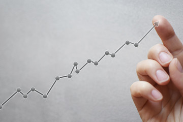 Business development and long term growing up revenue concept. Finger touching transparent arrow graph growth or increase business chart on light grey  background with copy space for text or image. 