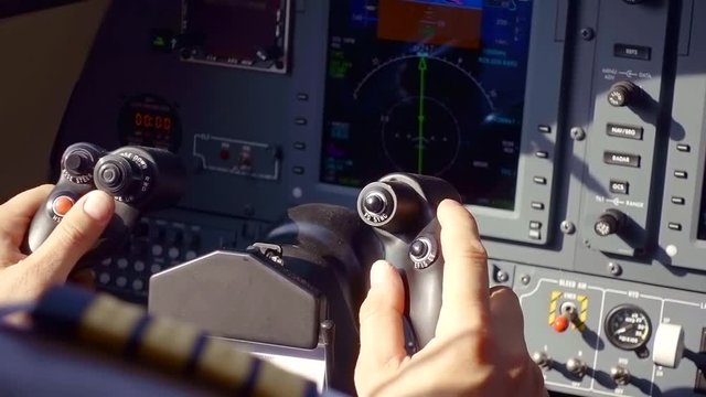 airman hands are holding a control of aircraft, close-up in a cabin of small airplane, monitor and buttons
