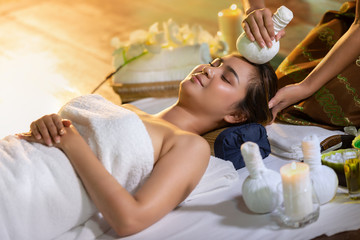 Obraz na płótnie Canvas Young Asia beautiful woman during massage with spa herbal compress with oil and herbal set near site, relaxing and healthy concept.