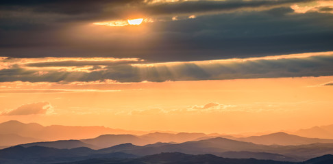 Obraz premium Amazing sunset in the mountains - beautiful golden light peaking through storm clouds with vivid colors and picturesque scenery - perfect relaxation spot