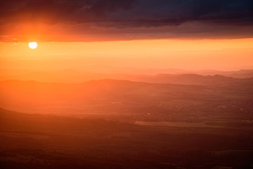 Amazing sunset in the mountains - beautiful golden light peaking through storm clouds with vivid colors and picturesque scenery - perfect relaxation spot