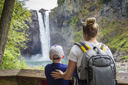 A family looking up at a beautiful scenic waterfall while on a day hike together outdoors.