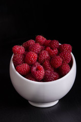 Bowl with raspberries on black backgound