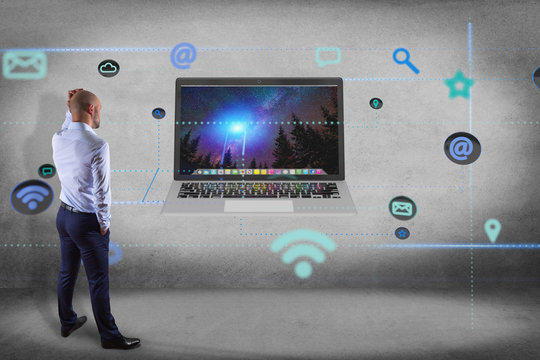 Businessman in front of a wall with a computer surrounding by app and social icon - 3d render