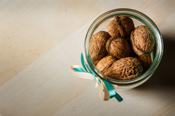 closeup standard open glass jar filled with whole walnuts
