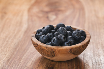 Fresh blueberries in wood bowl on table slightly toned