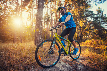 Fototapeta na wymiar bearded man cyclist rides in the forest on a mountain bike.