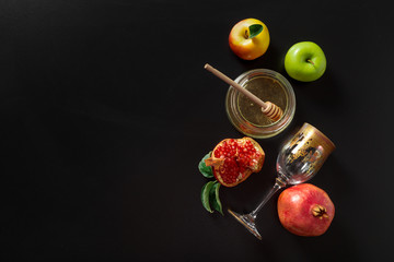 Pomegranate, apple and Honey for traditional holiday symbols Rosh hashanah (jewish new year holiday) on black background