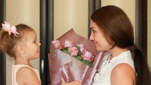 Mother and her child girl with a bouquet of flowers roses.