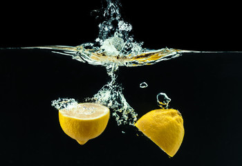 fresh yellow lemon in water splash on black background