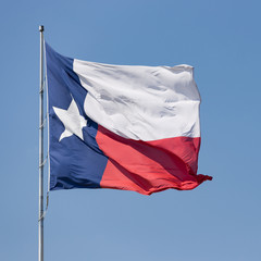 State flag of Texas waving against blue sky on a Windy Day. Blue sky background with copy space.